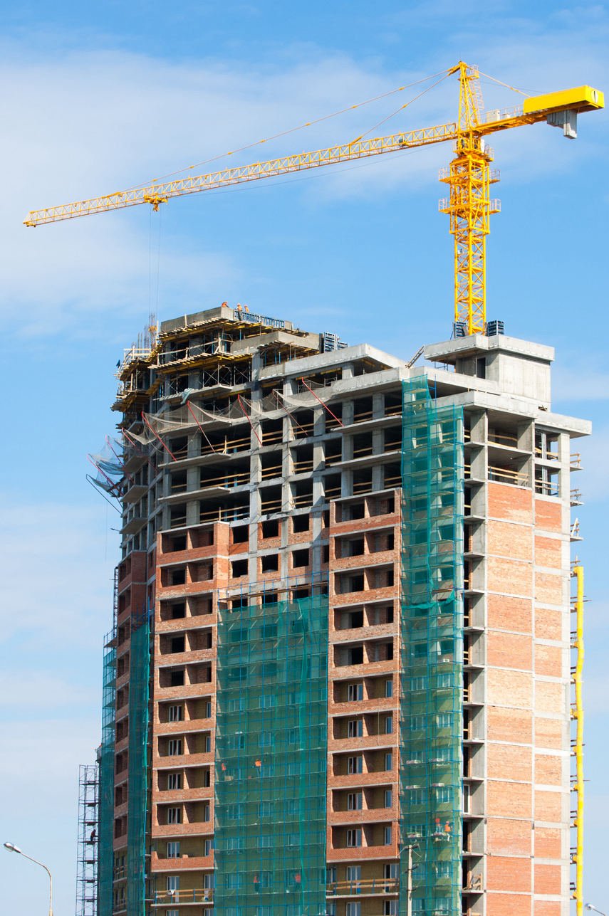 Edifício residencial em fase de estrutura, com grua e telas de proteção